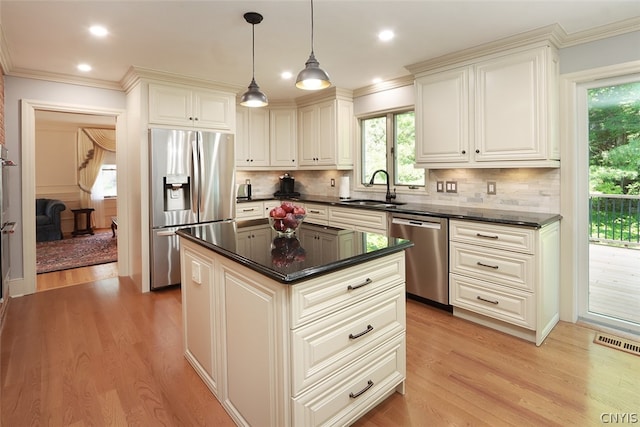 kitchen with tasteful backsplash, sink, a center island, appliances with stainless steel finishes, and light hardwood / wood-style flooring