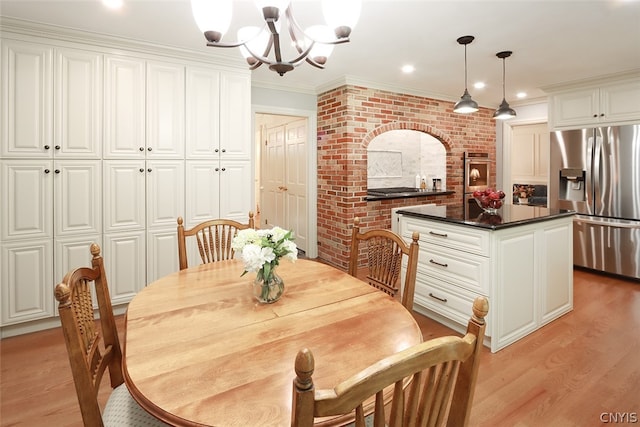 dining room with a notable chandelier, brick wall, crown molding, and light wood-type flooring