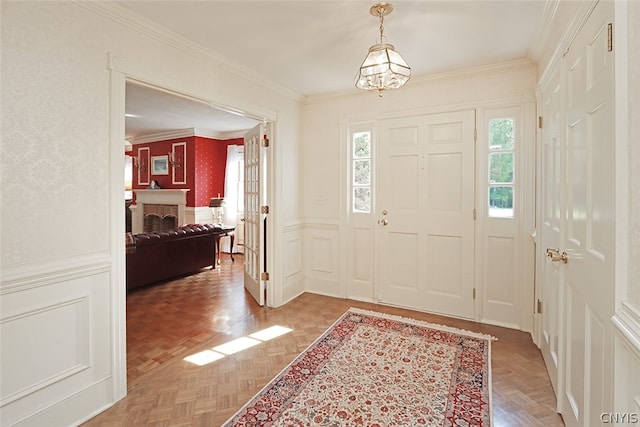 foyer entrance with an inviting chandelier, parquet flooring, and ornamental molding