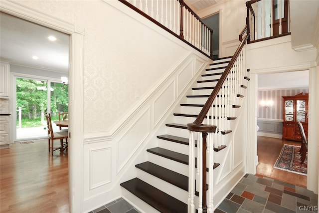 stairway with ornamental molding and hardwood / wood-style flooring