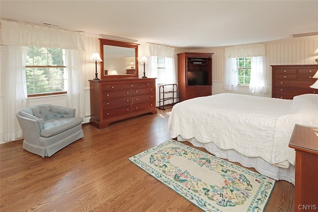 bedroom with hardwood / wood-style flooring and baseboard heating