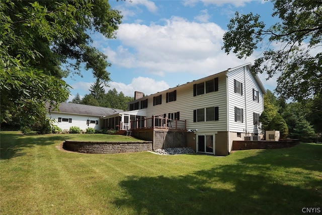 back of property featuring a deck and a lawn