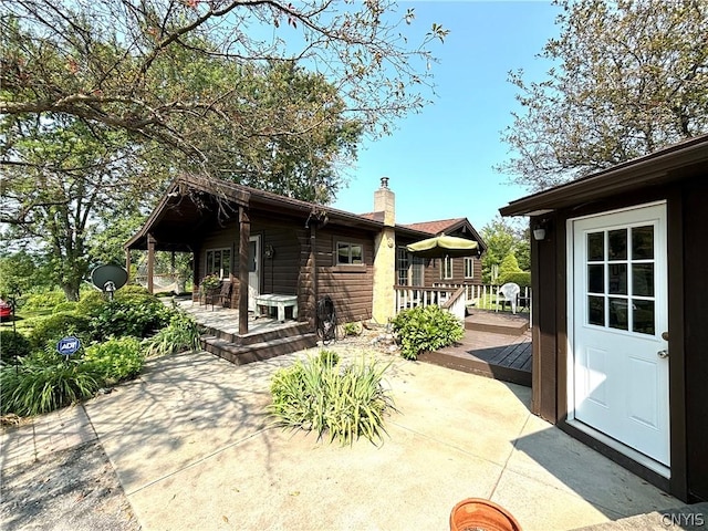 back of house with a wooden deck and a patio