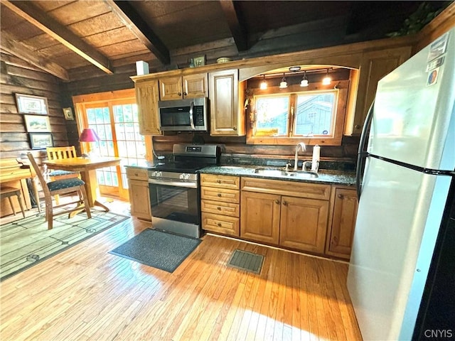 kitchen featuring appliances with stainless steel finishes, wooden walls, sink, wood ceiling, and light hardwood / wood-style flooring