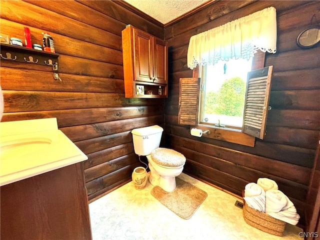 bathroom with vanity, log walls, a textured ceiling, and toilet