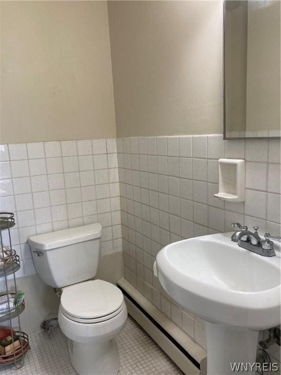 half bath featuring tile patterned floors, toilet, tile walls, and a baseboard radiator