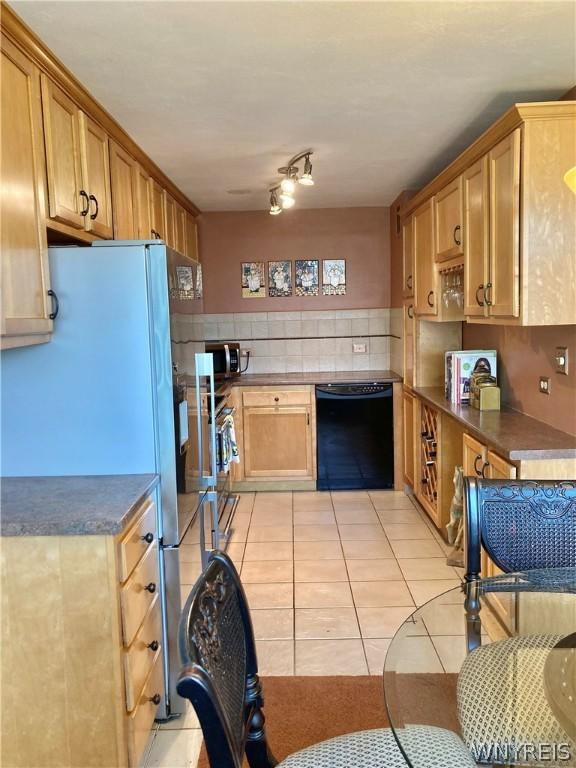 kitchen featuring stainless steel microwave, tasteful backsplash, black dishwasher, dark countertops, and light tile patterned floors