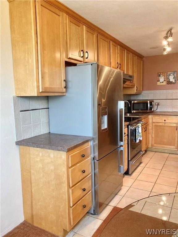 kitchen featuring under cabinet range hood, decorative backsplash, dark countertops, and appliances with stainless steel finishes