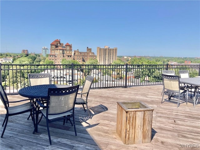 wooden terrace featuring outdoor dining space and a city view