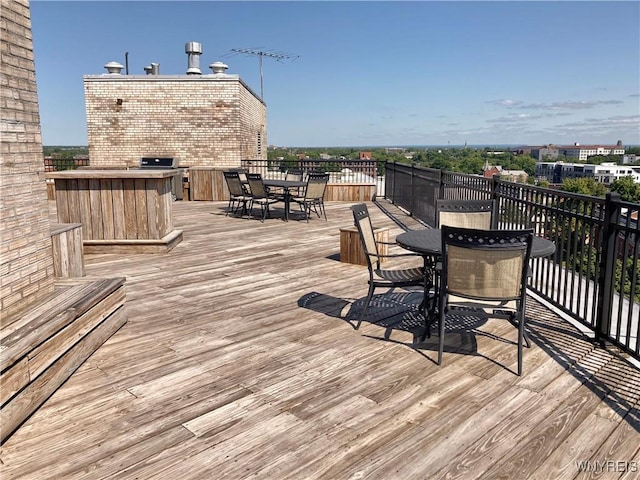 wooden terrace featuring outdoor dining space and grilling area