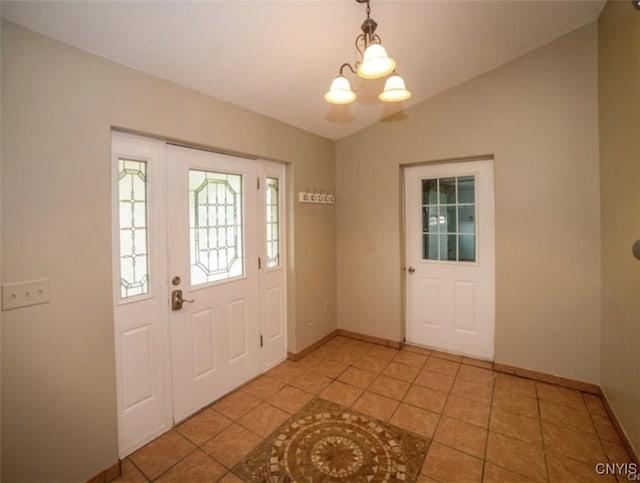 tiled foyer entrance featuring an inviting chandelier