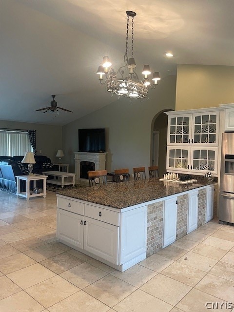 kitchen featuring white cabinets, ceiling fan with notable chandelier, stainless steel fridge, and vaulted ceiling