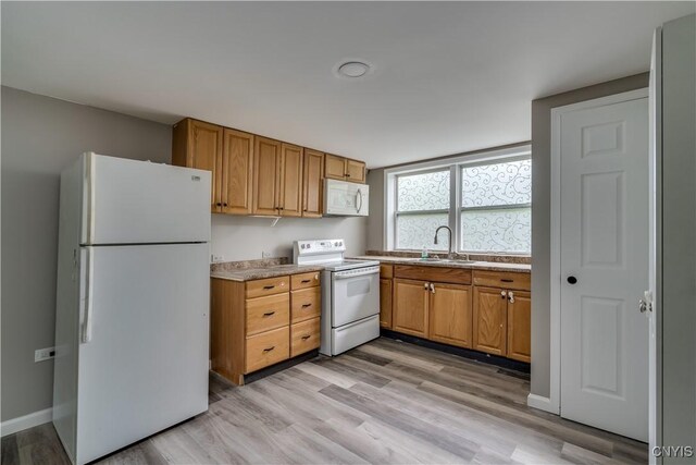 kitchen featuring sink, light wood-type flooring, and white appliances