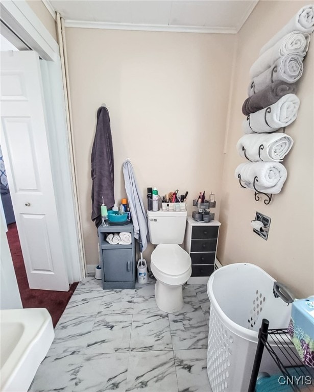 bathroom with tile patterned flooring, crown molding, toilet, and a bathtub