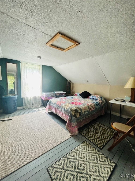 bedroom featuring hardwood / wood-style flooring, vaulted ceiling, and a textured ceiling