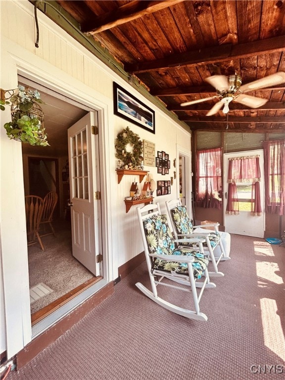 living area featuring carpet, beamed ceiling, and wooden ceiling