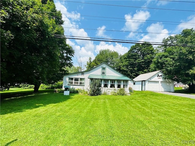 view of front facade featuring a garage, a front lawn, and an outbuilding