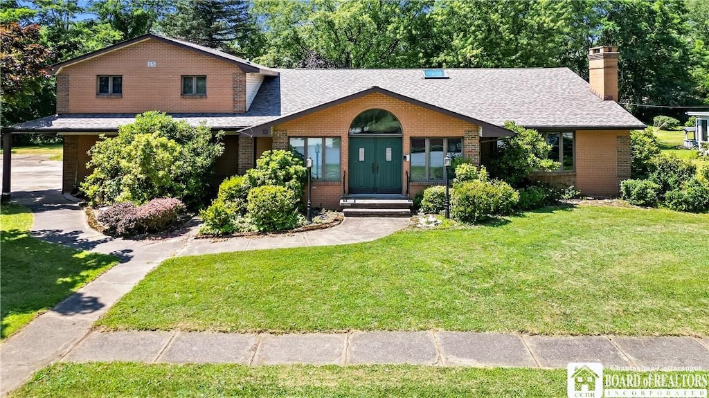 view of front of house with a front lawn, a chimney, brick siding, and a shingled roof