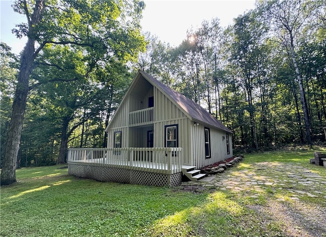 view of home's exterior with a balcony, a yard, and a wooden deck