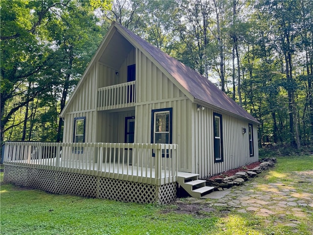 view of side of property featuring a balcony, a deck, and a lawn