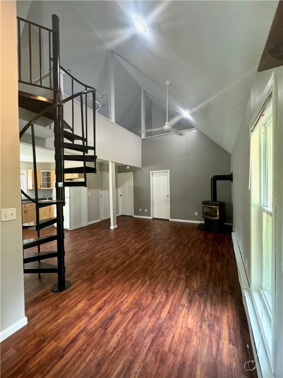 unfurnished living room with a wood stove, wood-type flooring, and ceiling fan