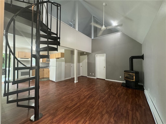 unfurnished living room featuring a wood stove, baseboard heating, high vaulted ceiling, and dark wood-type flooring