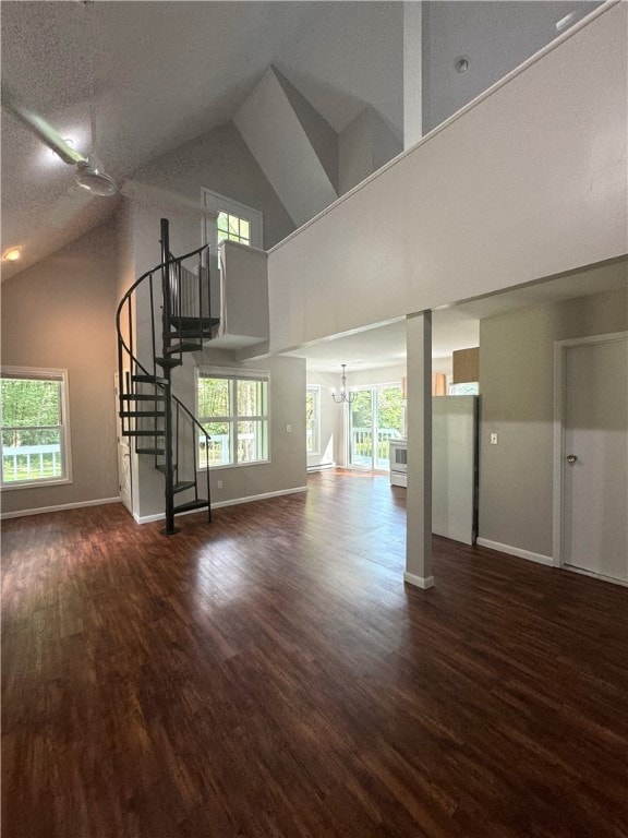 unfurnished living room with dark hardwood / wood-style floors, a textured ceiling, and high vaulted ceiling