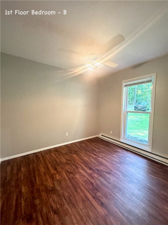 empty room featuring wood-type flooring, a baseboard radiator, and ceiling fan