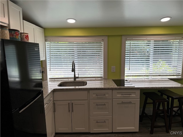 kitchen featuring sink, white cabinets, black appliances, and light stone countertops