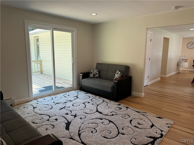 living room with a baseboard heating unit and wood-type flooring