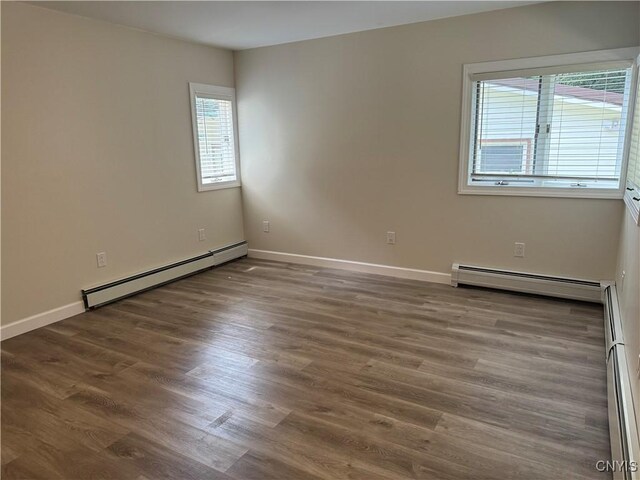 empty room with hardwood / wood-style flooring and a baseboard radiator