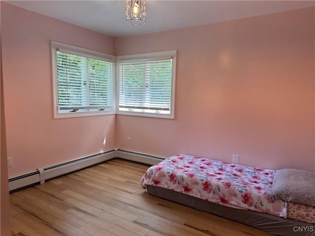 unfurnished bedroom with light hardwood / wood-style floors and baseboard heating