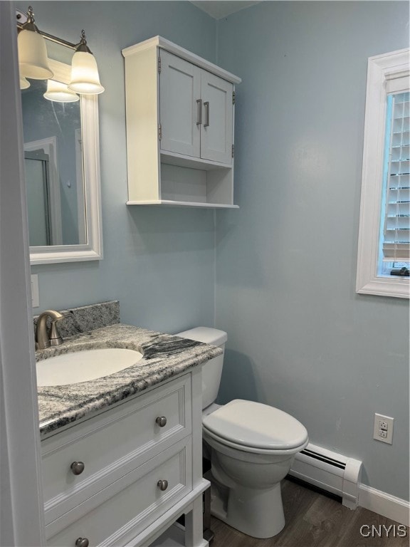 bathroom with wood-type flooring, toilet, vanity, and a baseboard radiator