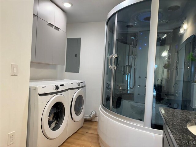 washroom with light wood-type flooring, washer and dryer, and electric panel