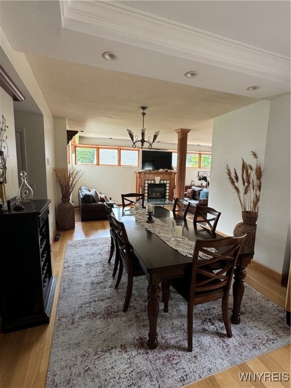 dining space featuring a fireplace, light wood-type flooring, and ornamental molding