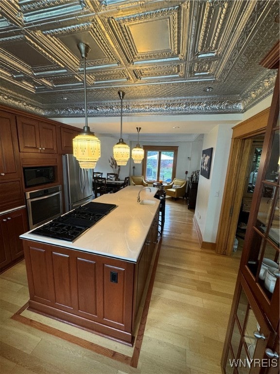 kitchen featuring stainless steel appliances, light hardwood / wood-style flooring, hanging light fixtures, and a kitchen island