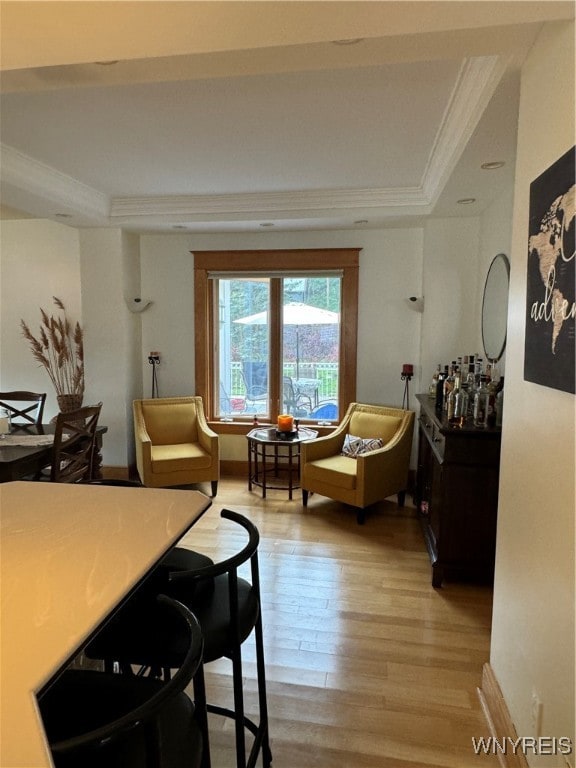 dining space with crown molding, a tray ceiling, and light hardwood / wood-style flooring