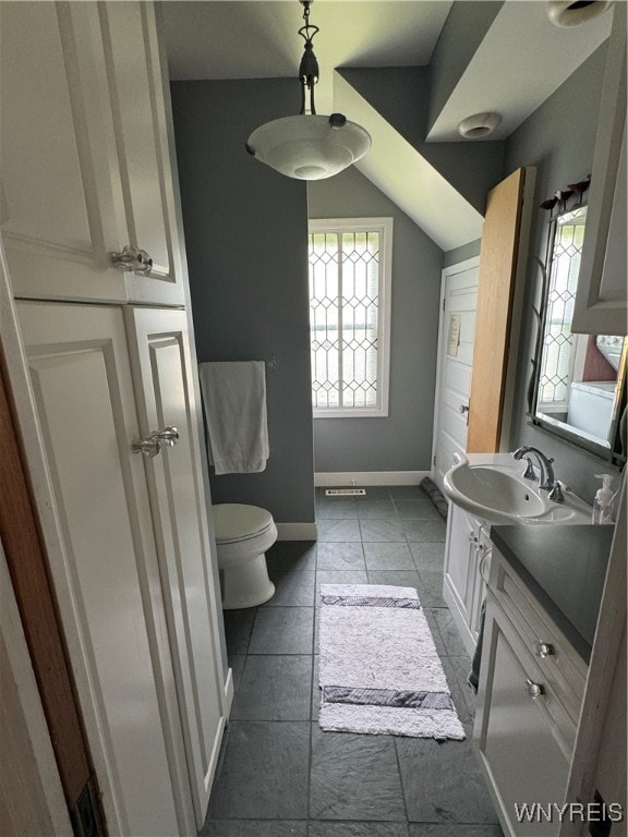 bathroom featuring tile patterned flooring, vaulted ceiling, toilet, and vanity