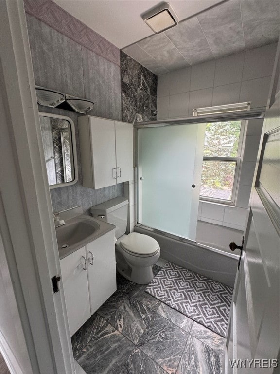 bathroom featuring tile patterned flooring, tile walls, toilet, and vanity