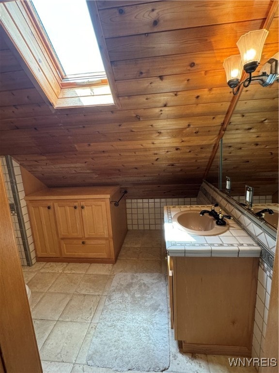 bathroom with tile patterned floors, vaulted ceiling with skylight, vanity, and wooden ceiling