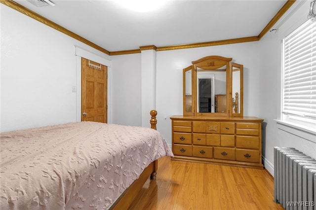 bedroom with crown molding, radiator, and light hardwood / wood-style floors