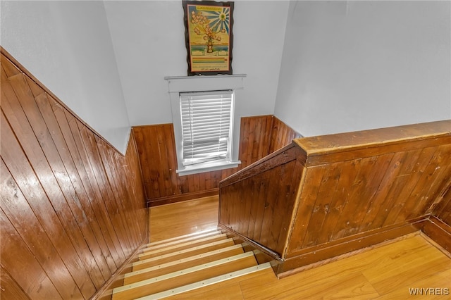 staircase featuring hardwood / wood-style floors and wooden walls