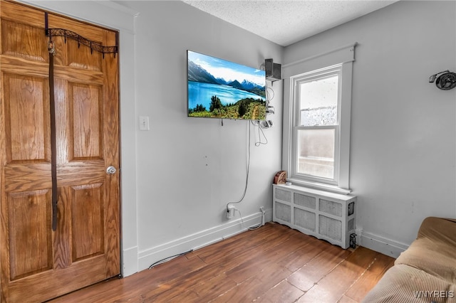 interior space featuring radiator, wood-type flooring, and a textured ceiling