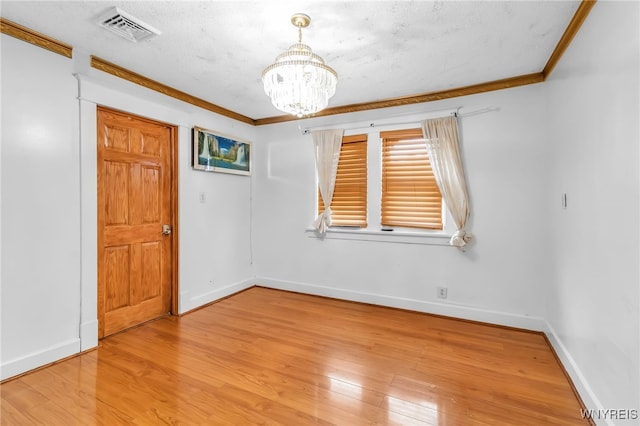 unfurnished room featuring a notable chandelier, light hardwood / wood-style flooring, ornamental molding, and a textured ceiling