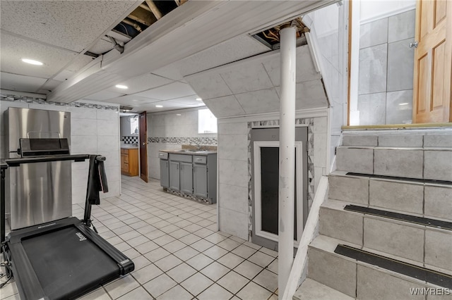 kitchen featuring sink, light tile patterned floors, gray cabinets, tile walls, and a drop ceiling