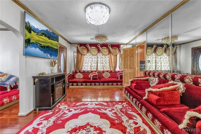 living room featuring hardwood / wood-style flooring, ornamental molding, and a textured ceiling