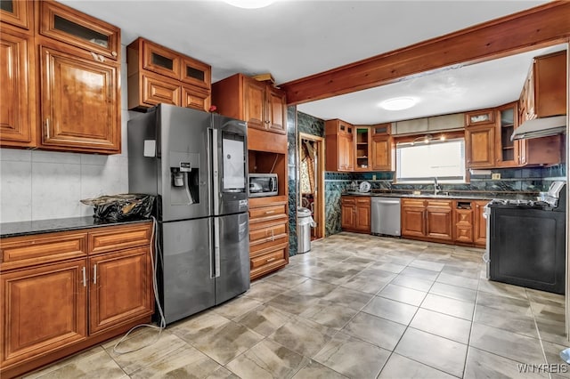 kitchen with sink, dark stone countertops, beamed ceiling, stainless steel appliances, and backsplash