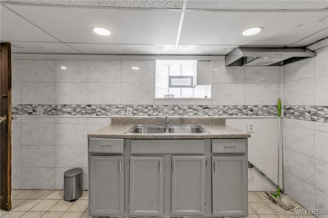 kitchen featuring sink, light tile patterned floors, gray cabinetry, tile walls, and wall chimney exhaust hood