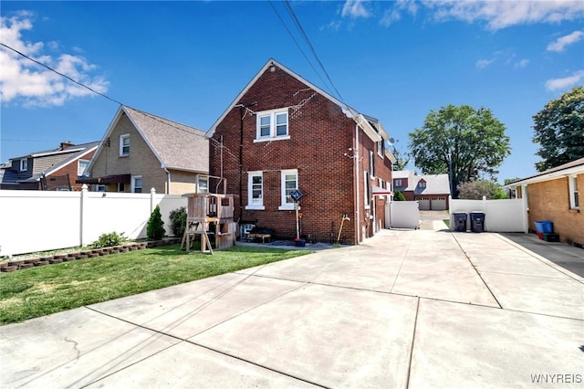 back of house with a yard and a playground