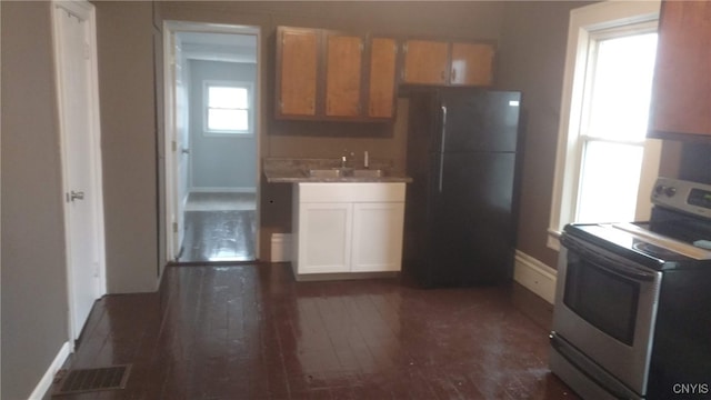 kitchen featuring sink, dark wood-type flooring, black fridge, and range with electric stovetop